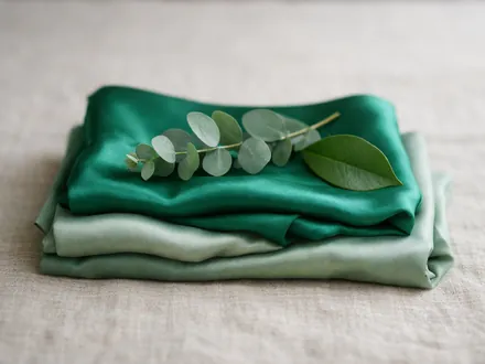 Una seta verde piegata con un rametto di eucalipto e una foglia