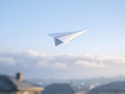Avião de papel branco a planar num céu azul-claro sobre os telhados - carácter de Gémeos