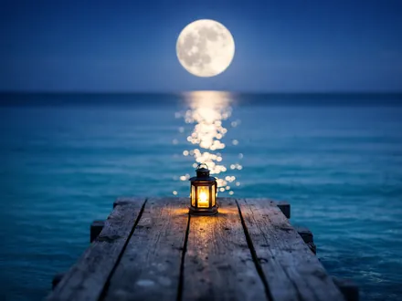 Lua cheia refletida num mar turquesa calmo a partir de um pontão com uma lanterna - personalidade do Caranguejo